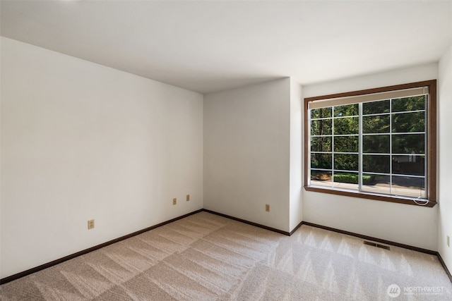 empty room with light colored carpet, baseboards, and visible vents