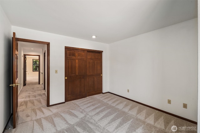 unfurnished bedroom featuring a closet, baseboards, and light carpet