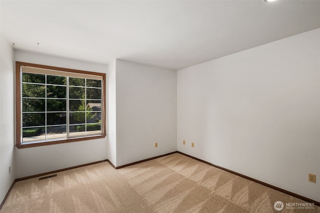 empty room with baseboards, visible vents, and light colored carpet