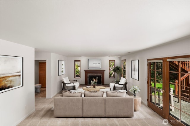 living room with baseboards, a fireplace, and light colored carpet
