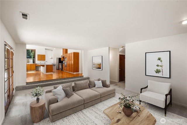 living area with light colored carpet, baseboards, and visible vents