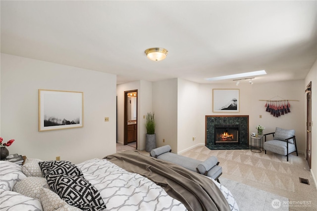 bedroom featuring light colored carpet, visible vents, and a tiled fireplace