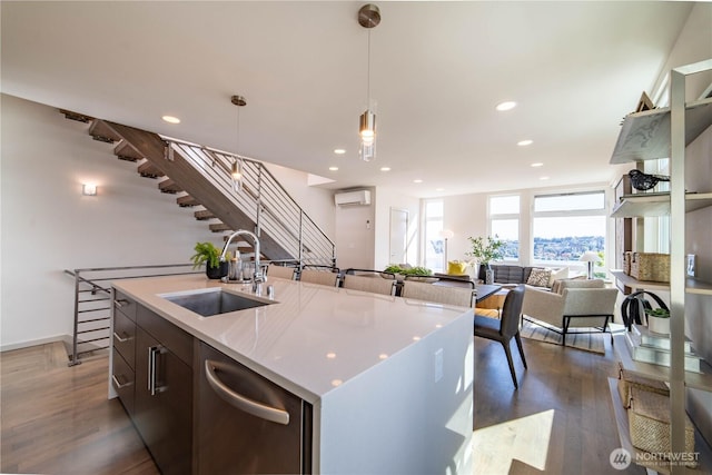 kitchen featuring stainless steel dishwasher, a sink, recessed lighting, dark wood finished floors, and a wall mounted air conditioner