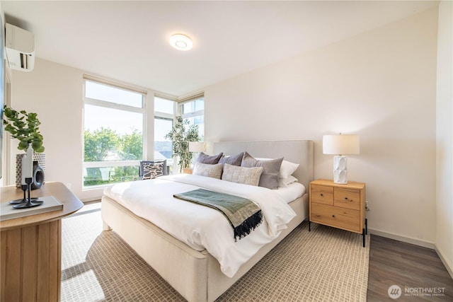 bedroom featuring wood finished floors, an AC wall unit, and baseboards
