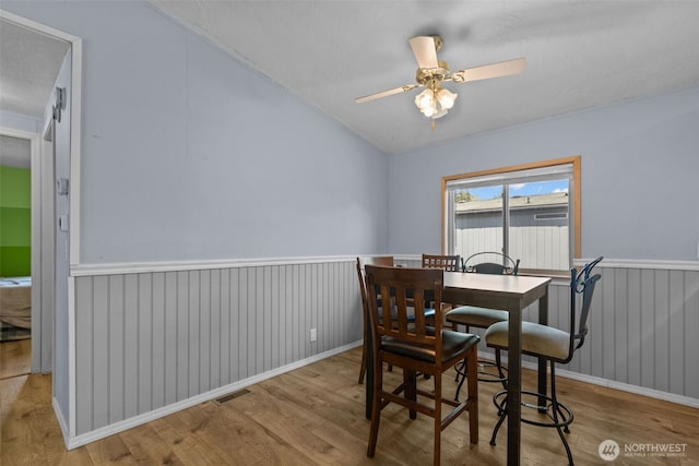 11519 21st Ave E Unit 84, Tacoma, WA 98445 - dining space with lofted ceiling, a wainscoted wall, wood finished floors, visible vents, and ceiling fan