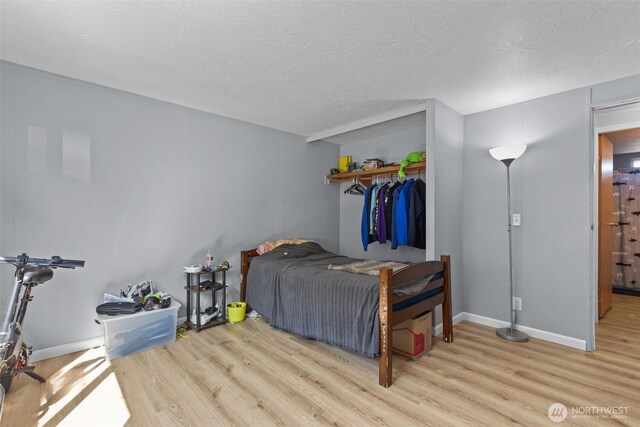 11519 21st Ave E Unit 84, Tacoma, WA 98445 - bedroom featuring a closet, a textured ceiling, wood finished floors, and baseboards