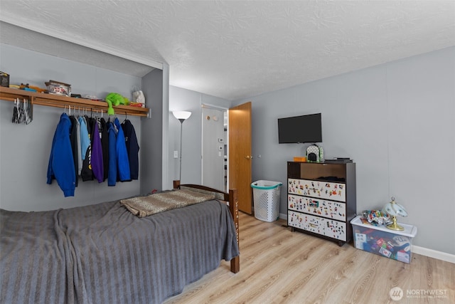 11519 21st Ave E Unit 84, Tacoma, WA 98445 - bedroom featuring a closet, a textured ceiling, wood finished floors, and baseboards