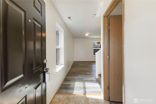 corridor featuring visible vents, light wood-style flooring, and baseboards