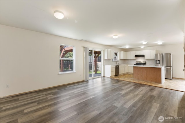 kitchen with wood finished floors, appliances with stainless steel finishes, light countertops, white cabinets, and under cabinet range hood