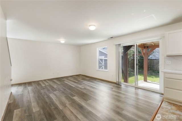 spare room featuring baseboards and wood finished floors