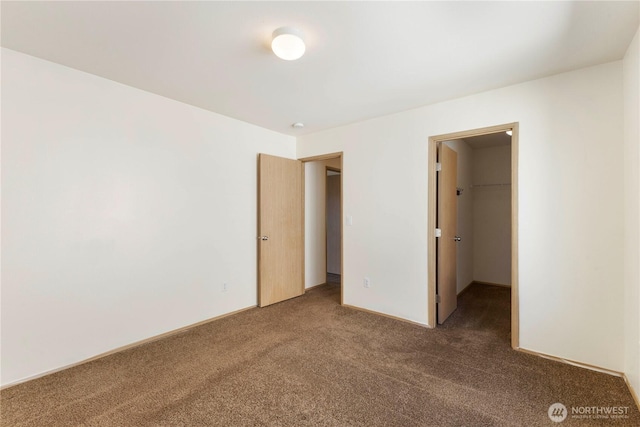 unfurnished bedroom with a spacious closet, carpet, and a closet
