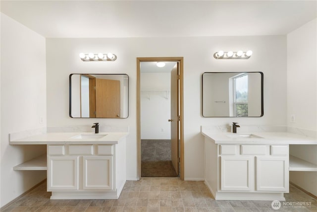 bathroom featuring two vanities, baseboards, and a sink