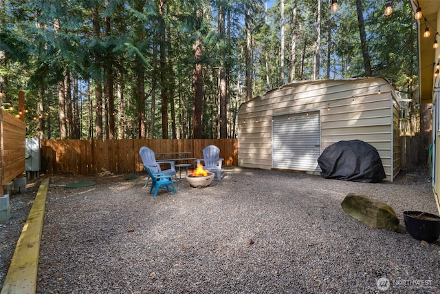 view of shed with a fenced backyard and a fire pit