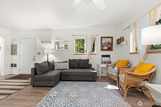 living room with electric panel, visible vents, baseboards, a ceiling fan, and wood finished floors
