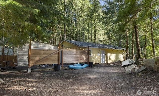 view of outdoor structure featuring fence and a view of trees