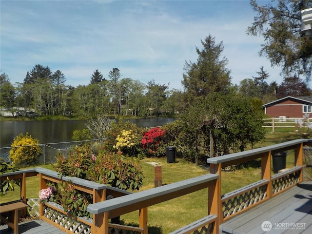wooden deck featuring a water view, fence, and a lawn