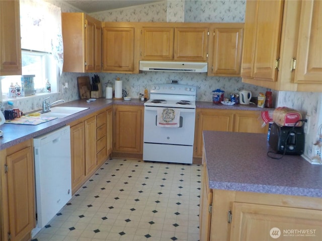 kitchen with a sink, white appliances, light floors, under cabinet range hood, and wallpapered walls