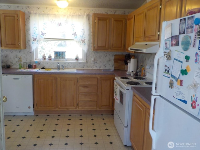 kitchen featuring white appliances, a sink, wallpapered walls, and under cabinet range hood