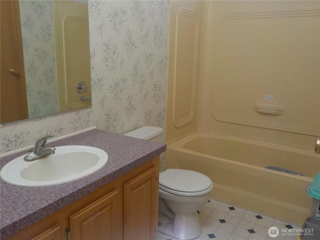 full bath with vanity, toilet,  shower combination, and wallpapered walls