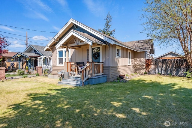 bungalow-style house with fence, board and batten siding, and a front yard