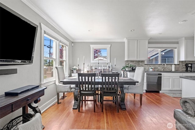 dining space with light wood-type flooring, ornamental molding, baseboards, and a wealth of natural light