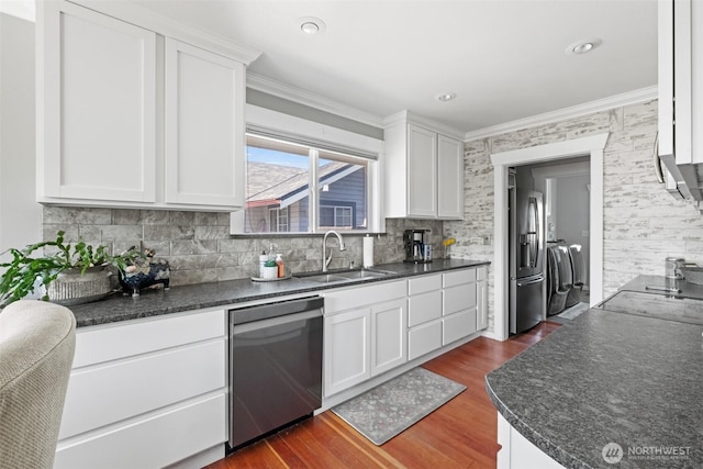 kitchen with a sink, appliances with stainless steel finishes, crown molding, and dark countertops