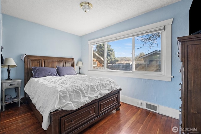 bedroom featuring dark wood-style flooring, baseboards, visible vents, and a textured ceiling