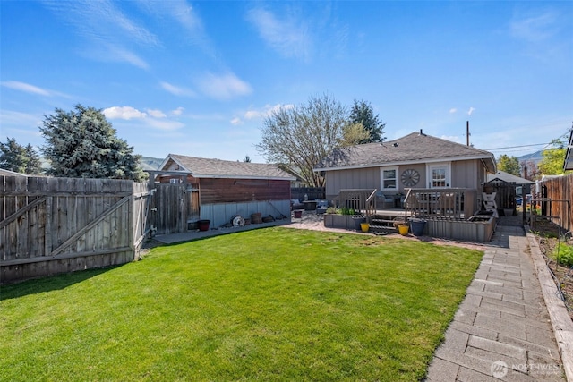 view of yard with a deck, an outbuilding, and a fenced backyard