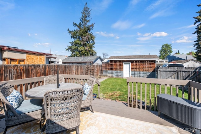 wooden terrace featuring a lawn, a fenced backyard, a storage unit, and an outdoor structure