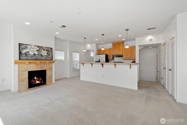 10757 NE Red Wing Way Unit 201, Hillsboro, OR 97006 - kitchen with freestanding refrigerator, light carpet, a breakfast bar, a fireplace, and recessed lighting