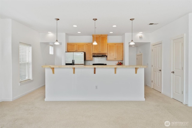10757 NE Red Wing Way Unit 201, Hillsboro, OR 97006 - kitchen featuring refrigerator, under cabinet range hood, light colored carpet, light countertops, and a breakfast bar area