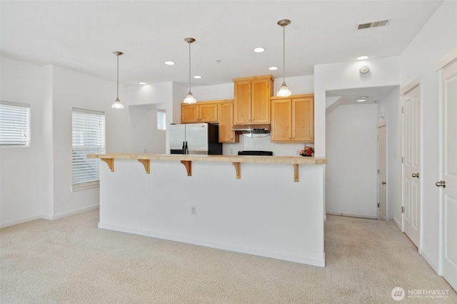 10757 NE Red Wing Way Unit 201, Hillsboro, OR 97006 - kitchen with freestanding refrigerator, light carpet, a kitchen breakfast bar, light countertops, and recessed lighting