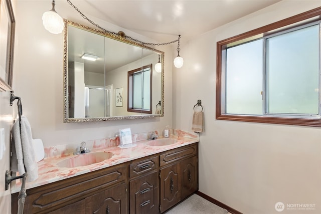 full bath featuring double vanity, baseboards, a sink, and a shower with shower door