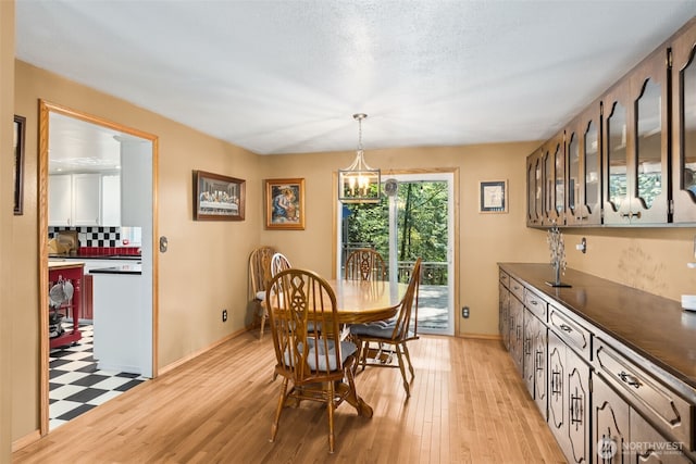dining area with light wood-style floors, baseboards, and a chandelier