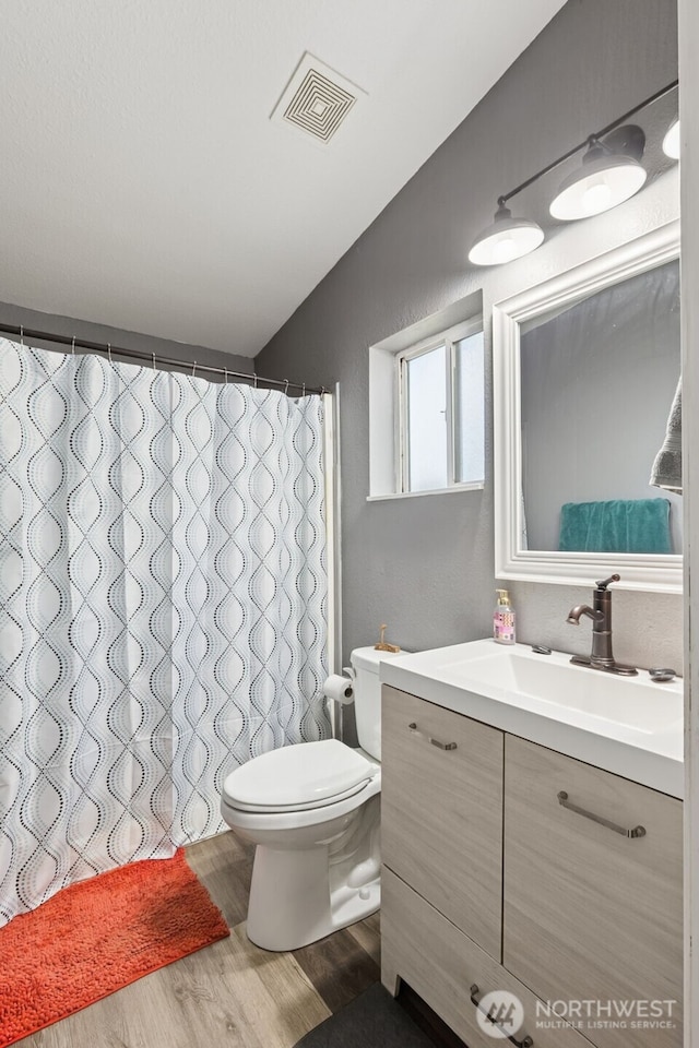 bathroom featuring vanity, toilet, curtained shower, wood finished floors, and visible vents
