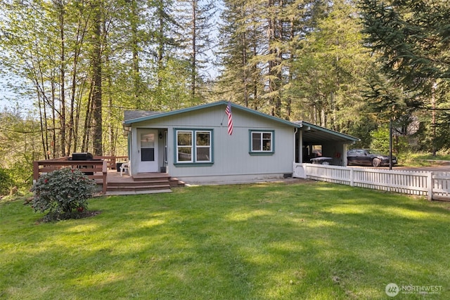 back of property with a lawn, a wooden deck, fence, and an attached carport