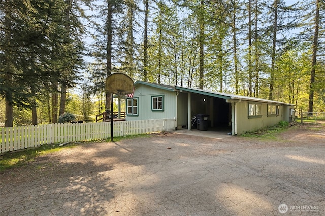 exterior space featuring fence, an attached carport, and aphalt driveway
