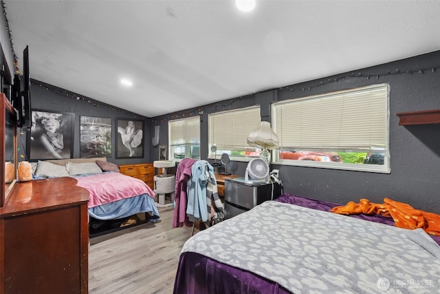 bedroom with vaulted ceiling, multiple windows, and wood finished floors