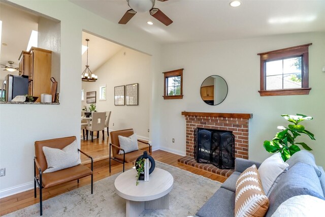 living room featuring ceiling fan with notable chandelier, plenty of natural light, vaulted ceiling, and wood finished floors