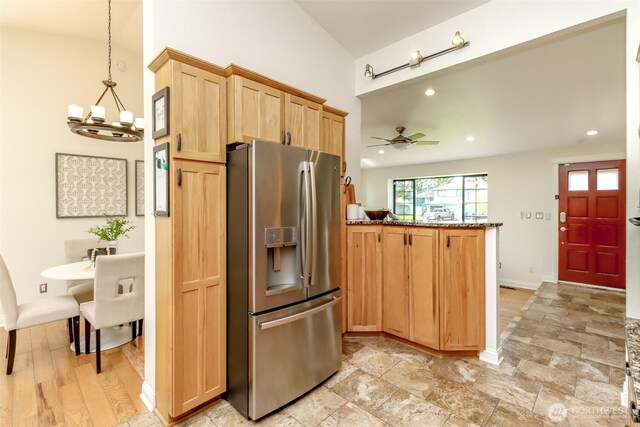 kitchen with a peninsula, light brown cabinetry, ceiling fan with notable chandelier, lofted ceiling, and stainless steel fridge with ice dispenser