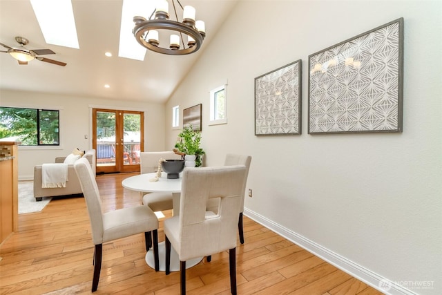 dining area featuring vaulted ceiling with skylight, french doors, light wood-style flooring, baseboards, and recessed lighting