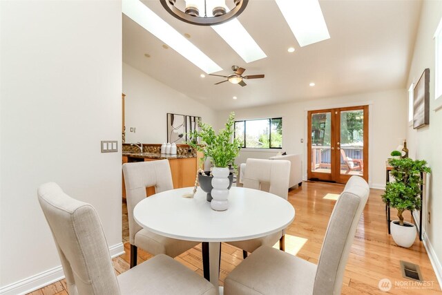 dining area with vaulted ceiling with skylight, light wood-style floors, french doors, visible vents, and recessed lighting
