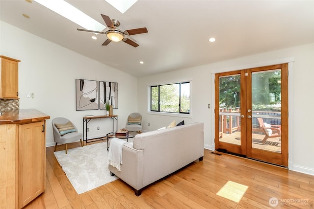 living area featuring light wood-style flooring, french doors, recessed lighting, and vaulted ceiling with skylight