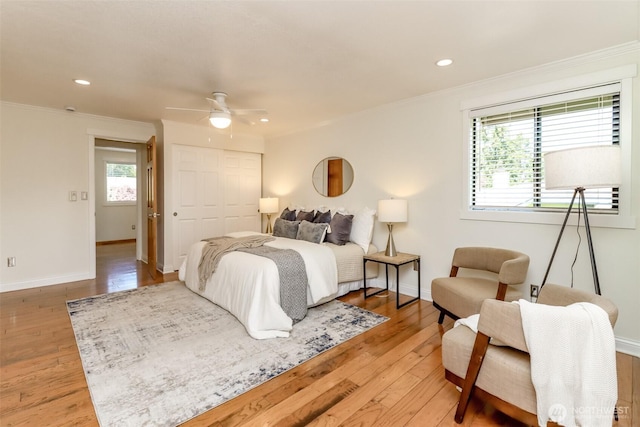bedroom with light wood-style flooring, baseboards, a closet, and ornamental molding