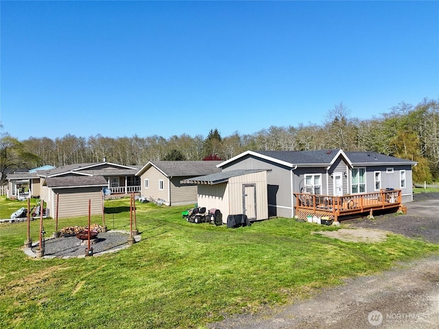 back of house with a lawn, a shed, an outdoor structure, and a deck