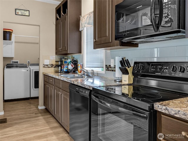 kitchen with washing machine and dryer, tasteful backsplash, a sink, and black appliances