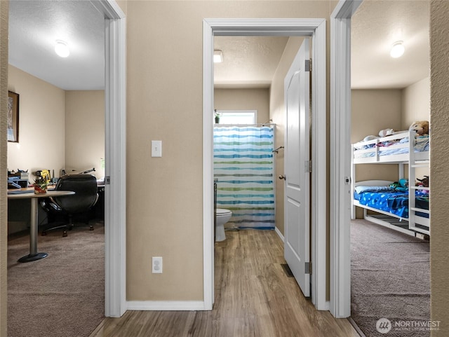 hall with baseboards, wood finished floors, and carpet flooring