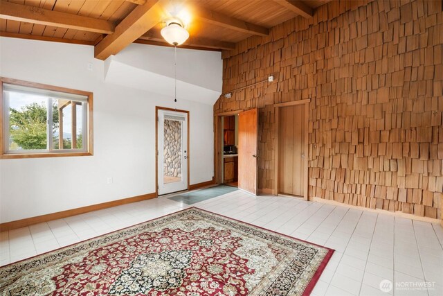 tiled spare room with wooden ceiling, beam ceiling, baseboards, high vaulted ceiling, and wood walls