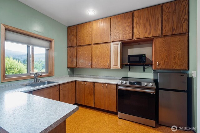 kitchen with appliances with stainless steel finishes, a sink, light countertops, and brown cabinets