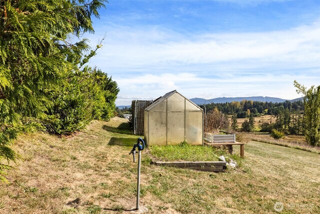 view of greenhouse featuring a yard and a mountain view